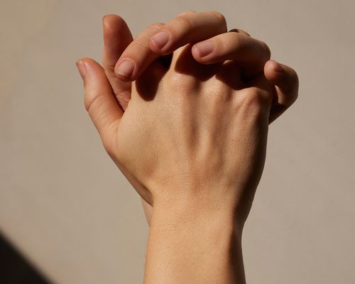 close up of a woman's hands clasped, bathed in shadows and light