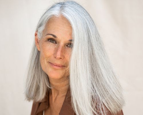 woman with light gray hair against neutral background