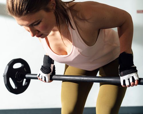 Woman does a deadlift while wearing gloves