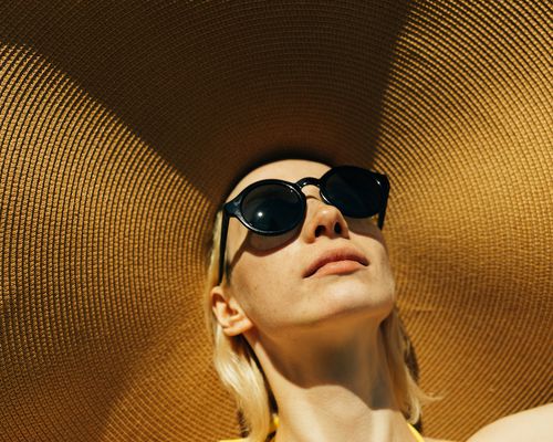 Woman wears a large hat and sunglasses outdoors