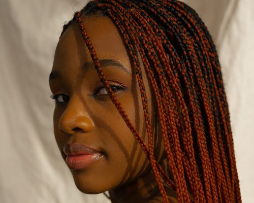 side view of woman with red braids looking at camera