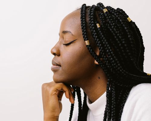 Side profile of a woman with long braids, hand on her chin, eyes closed