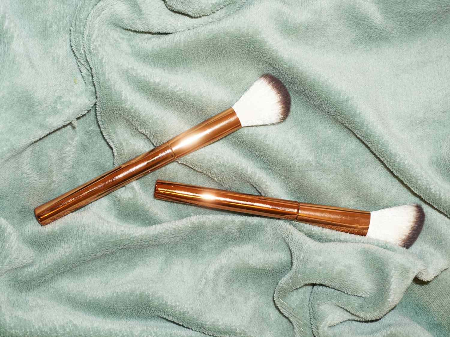 makeup brushes on light green background