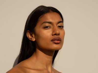 woman with olive skin standing against tan background