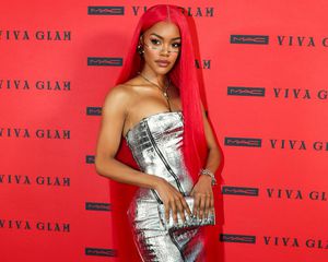 Teyana Taylor posing with long red hair in a silver dress with face jewelry and silver clutch