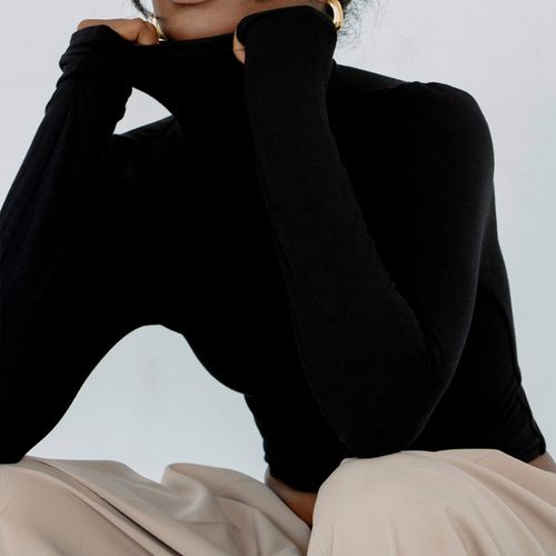 Re Ona Turtleneck Long Sleeve Top in black on model styled with beige trousers