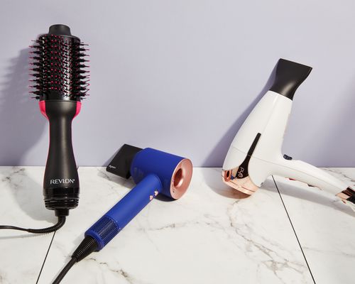 A side-by-side selection of blow dryers for fine hair displayed on a marbled surface