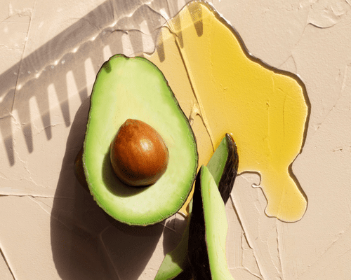 A close up of a comb, half an avocado and oil