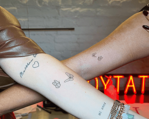 Close up of two arms with matching butterfly tattoos