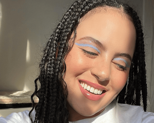 close up of woman smiling in purple eyeliner