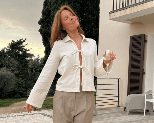 Close up of a model wearing a white tie up, long sleeve Copenhagen blouse.