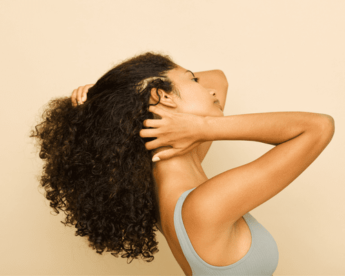 A woman's side profile as she touches her hair