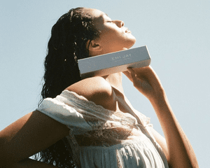 A woman holding up Emi Jay's Dream CrÃ©me hair mask.