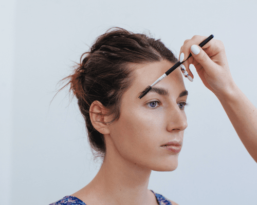 Close up of a woman brushing up eyebrows with spoolie