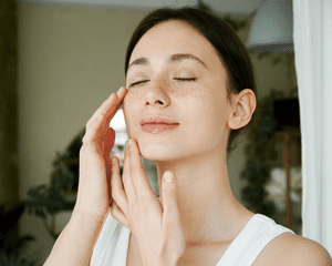 A woman with her eyes closed and her hands massaging her face