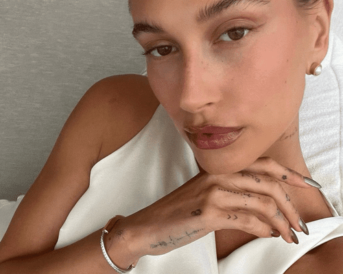 Close up of Hailey Bieber showing her hand and finger tattoos