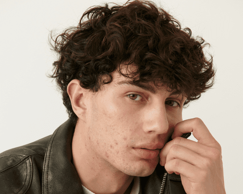 Close up of a male model with curly brown hair.