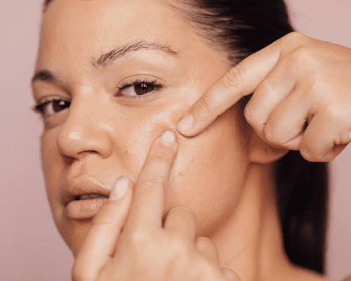 Close up of woman popping a pimple