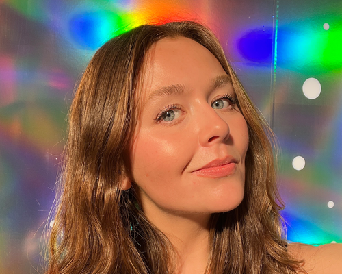 close up of woman with glowy makeup on rainbow background