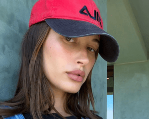 Hailey Bieber wearing a red Fila baseball cap.