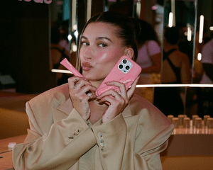 Hailey holding a lip gloss and phone. 