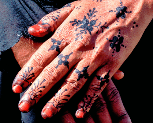 A model with dark floral henna designs on the hands. 