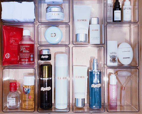 drawer of clear containers full of skincare and makeup