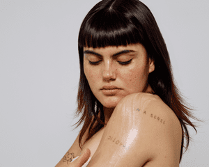 Close up of a woman looking down at her arm tattoos.