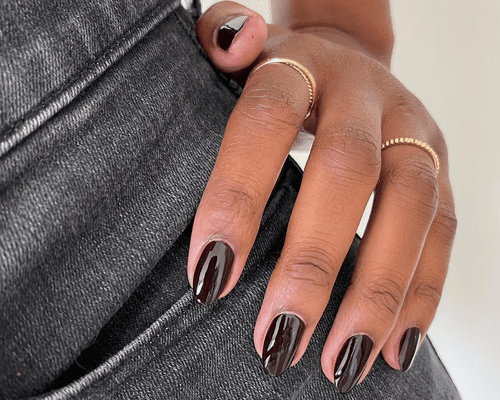 close up of woman's hand with black manicure against black jeans