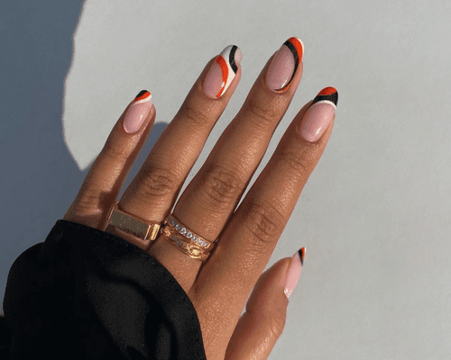 Oval shaped nails with black, orange, and white French tip swirls.