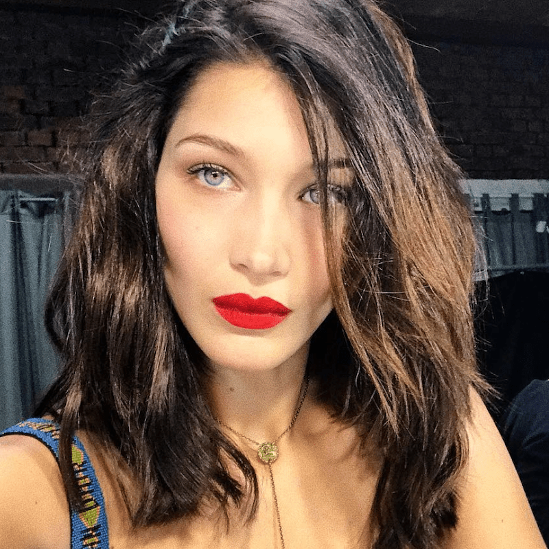 Bella Hadid wears a textured, tousled hairstyle and red lipstick