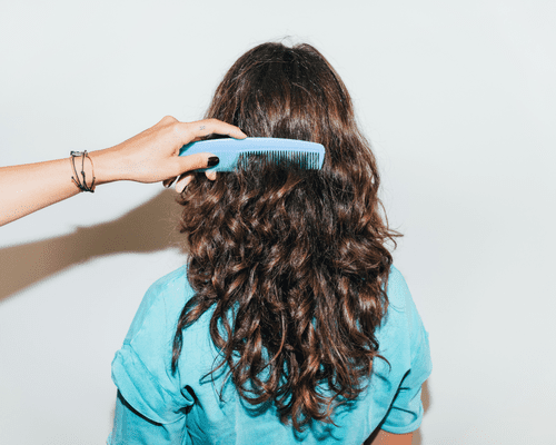 Close up of a comb going through a woman's wavy hair