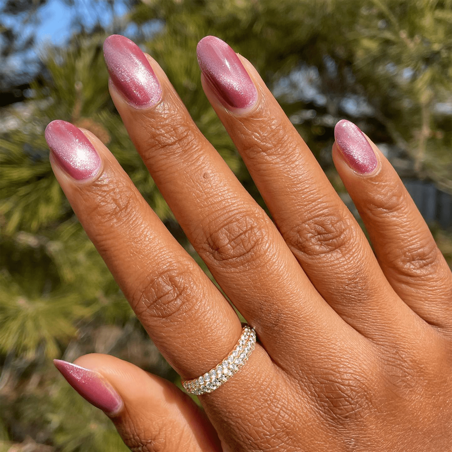 Hand with a diamond ring with rose chrome nails