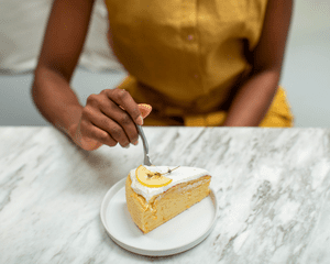 A woman's hand with a fork and a slice of cake