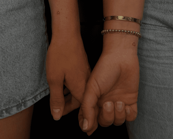 Close up of two wrists with matching red heart tattoos