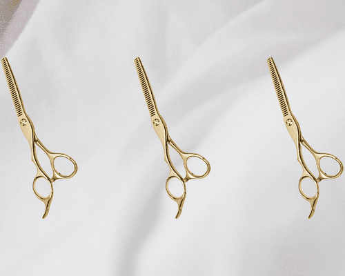 Three gold thinning shears on white background