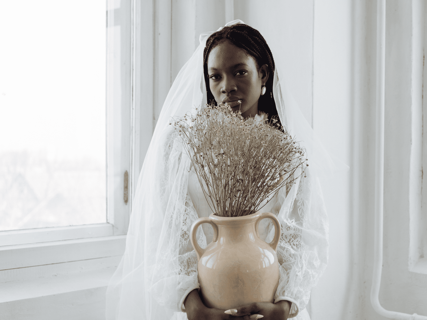 bride with long veil holding vase of flowers