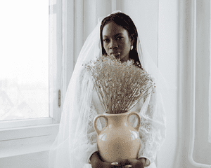 bride with long veil holding vase of flowers