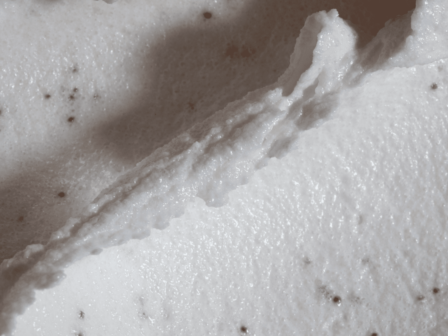 Close up of white haircare product, with pink beads. 